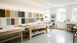 Atelier lumineux et moderne après rénovation : mur fraîchement refait, échantillons de revêtements rangés sur une table, outils et pinceaux visibles, éclairage LED doux et ambiance propre.